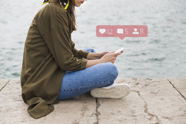 side-view-of-woman-sitting-on-pier-using-social-media-application-on-mobile-phone_23-2147844492