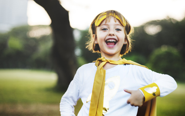 Young caucasian girl smiling  wearing superhero costume in the park