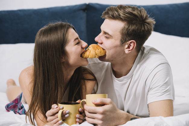 couple-eating-one-croissant-bed_23-2148027341